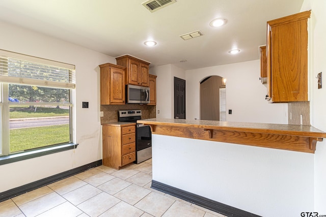 kitchen with tasteful backsplash, light tile patterned flooring, appliances with stainless steel finishes, and kitchen peninsula