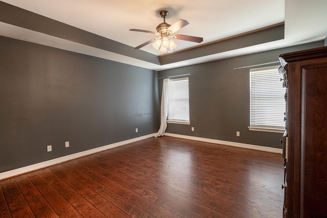 spare room with dark hardwood / wood-style floors, ceiling fan, and a tray ceiling