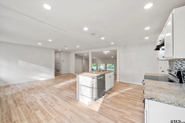 kitchen featuring appliances with stainless steel finishes, light stone counters, a center island with sink, and white cabinets