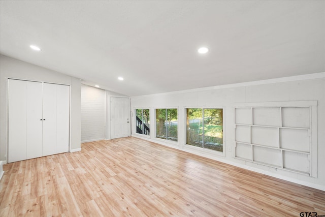 unfurnished bedroom with two closets, light wood-type flooring, and vaulted ceiling