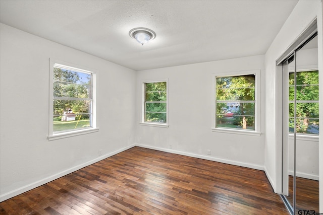 spare room featuring dark hardwood / wood-style flooring and a textured ceiling