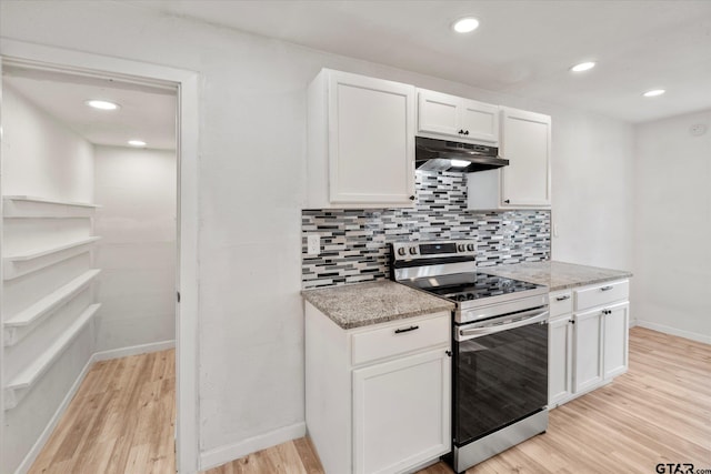 kitchen with tasteful backsplash, light stone counters, white cabinetry, stainless steel range, and light hardwood / wood-style floors