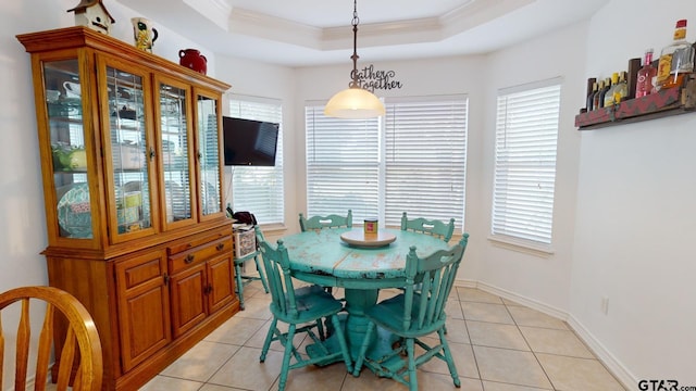 tiled dining room featuring a healthy amount of sunlight, a tray ceiling, and ornamental molding