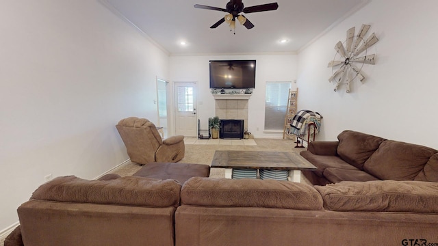 living room with a tiled fireplace, ceiling fan, and crown molding