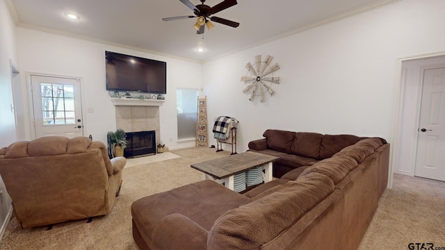 living room featuring ceiling fan, a tiled fireplace, light carpet, and crown molding