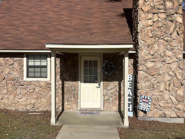 property entrance with stone siding and roof with shingles