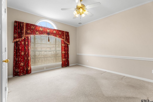 carpeted spare room with baseboards, ornamental molding, and a ceiling fan