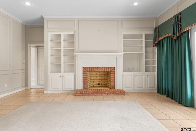 unfurnished living room with a brick fireplace, built in features, a decorative wall, and crown molding