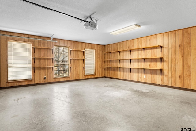 garage with baseboards, wood walls, and a garage door opener