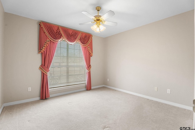 empty room with carpet floors, a ceiling fan, and baseboards