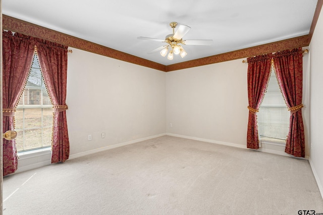 carpeted spare room featuring baseboards and a ceiling fan