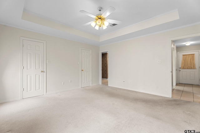 unfurnished room featuring light carpet, visible vents, and a tray ceiling