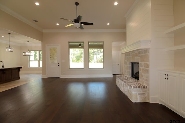 unfurnished living room with a fireplace, ceiling fan, dark wood-type flooring, and crown molding