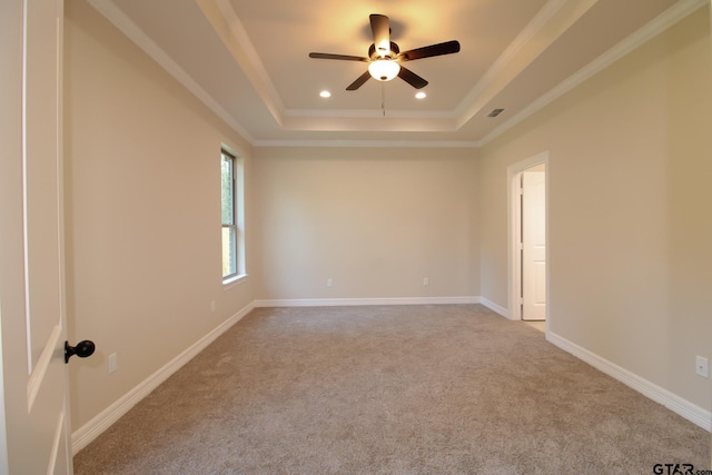 spare room with carpet, ceiling fan, crown molding, and a tray ceiling