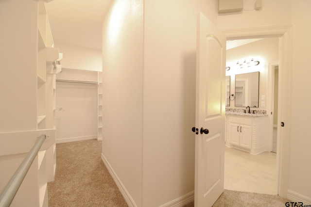 hall featuring light colored carpet and sink