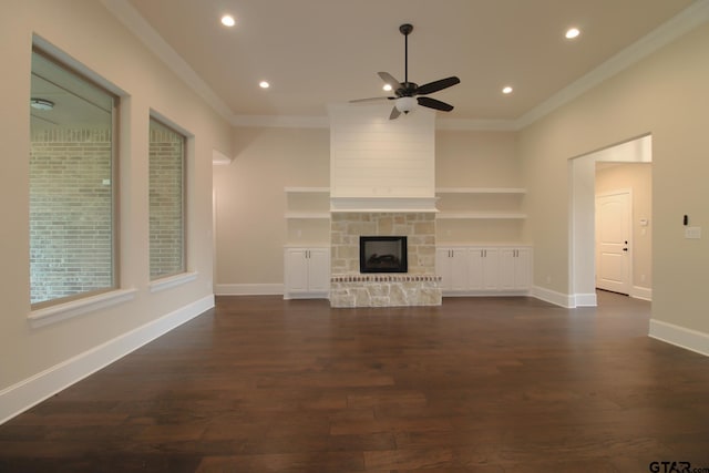 unfurnished living room with a stone fireplace, ceiling fan, dark hardwood / wood-style floors, and crown molding