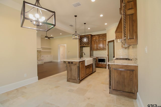 kitchen featuring ceiling fan with notable chandelier, decorative backsplash, sink, a kitchen island with sink, and pendant lighting