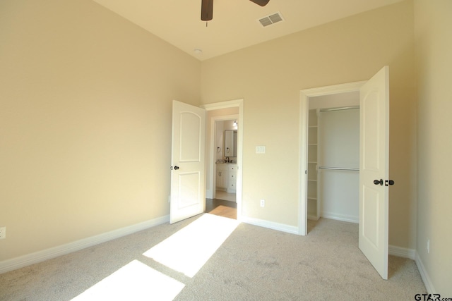 unfurnished bedroom with ceiling fan, light carpet, a closet, and a spacious closet