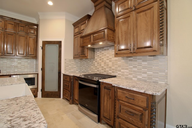 kitchen with ornamental molding, custom range hood, stove, and tasteful backsplash