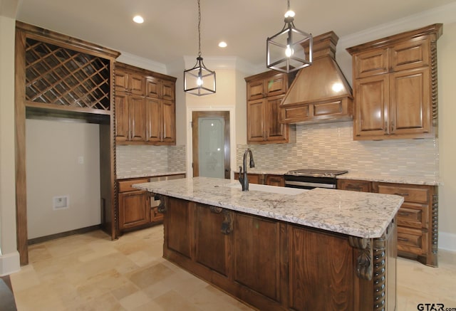 kitchen with stainless steel range oven, an island with sink, custom range hood, backsplash, and pendant lighting