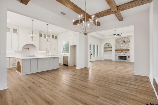 kitchen featuring a large fireplace, a kitchen island, white cabinetry, light hardwood / wood-style flooring, and decorative light fixtures