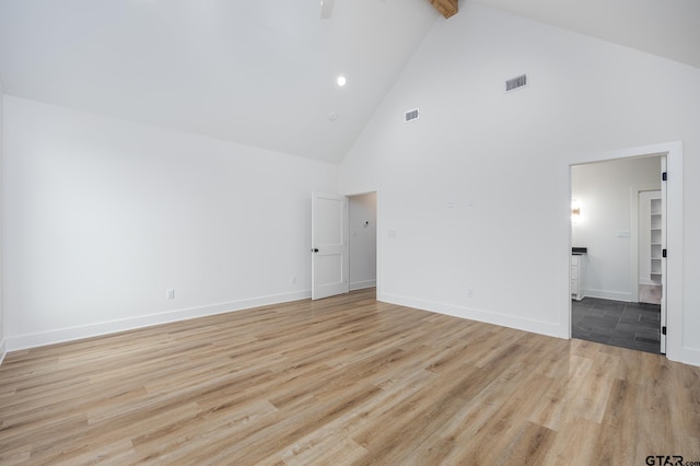 unfurnished room with light wood-type flooring, beamed ceiling, and high vaulted ceiling