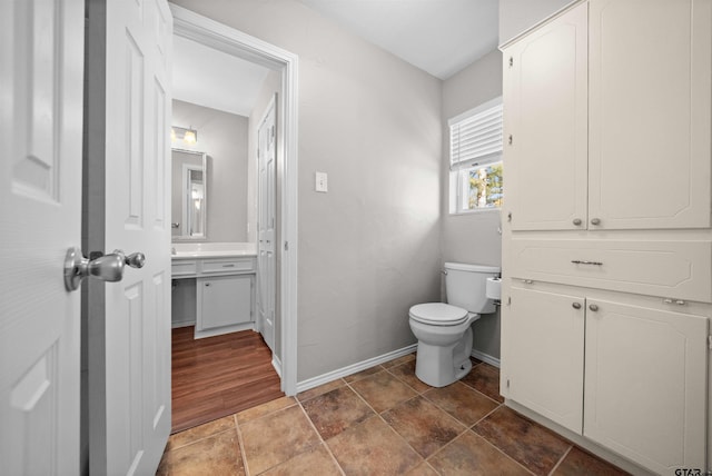 bathroom featuring toilet, baseboards, and vanity