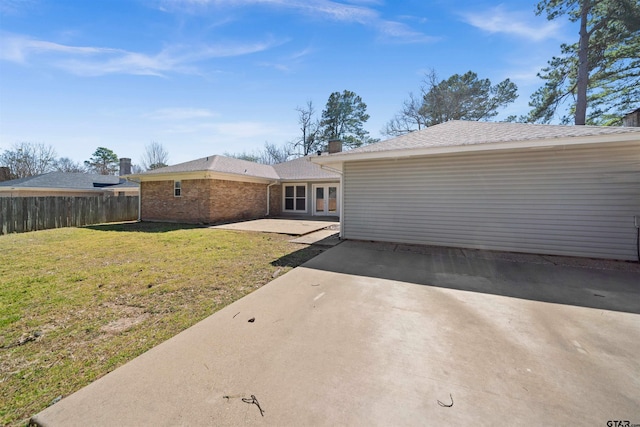 rear view of property featuring fence, a yard, french doors, driveway, and a patio area