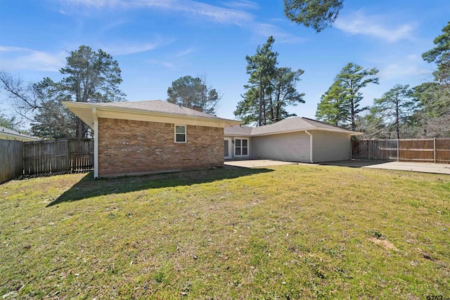 back of house with a yard, brick siding, and a patio