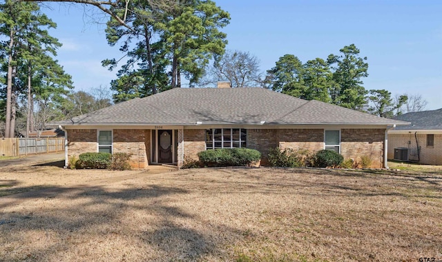 single story home featuring central air condition unit, a shingled roof, brick siding, fence, and a chimney