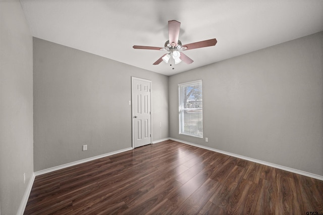 spare room featuring dark wood-type flooring, ceiling fan, and baseboards