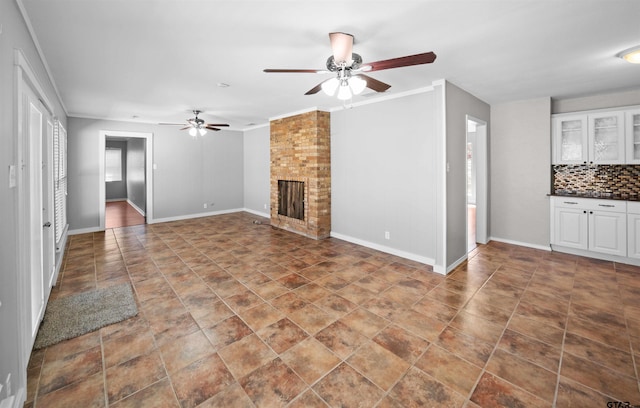 unfurnished living room featuring baseboards, a fireplace, and crown molding