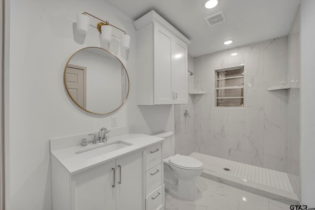 bathroom with toilet, vanity, and tiled shower