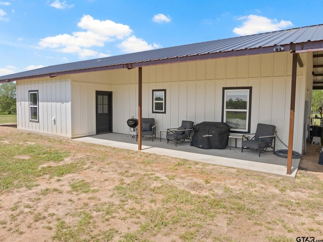 back of property with a patio, board and batten siding, and metal roof