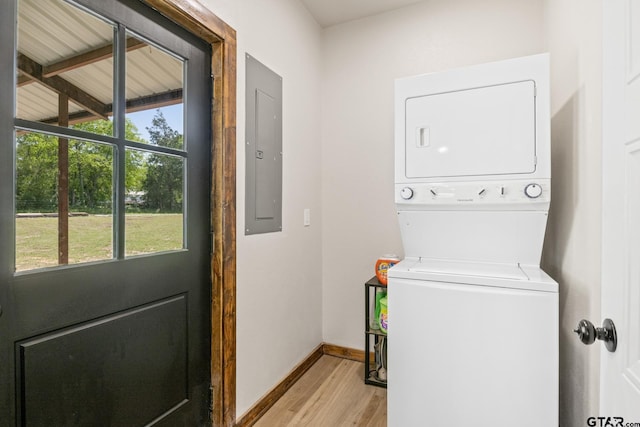 laundry room with baseboards, electric panel, stacked washer / dryer, laundry area, and light wood-style floors