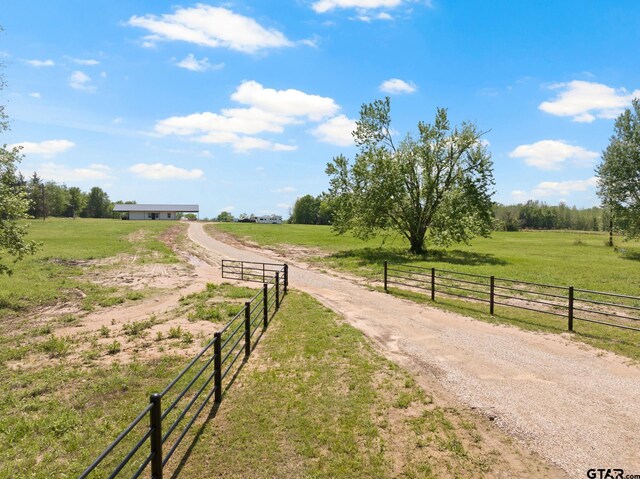 view of home's community featuring a rural view, a yard, and fence