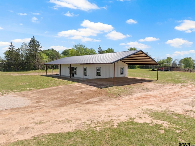 view of front facade featuring metal roof, driveway, a detached carport, and a front lawn