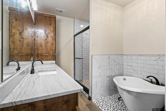 full bath featuring tile walls, a stall shower, visible vents, and a freestanding bath