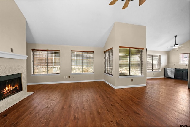 unfurnished living room with dark hardwood / wood-style flooring, a tile fireplace, and ceiling fan