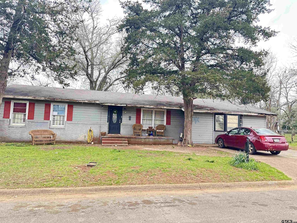 ranch-style house featuring a front lawn, concrete driveway, brick siding, and an attached garage