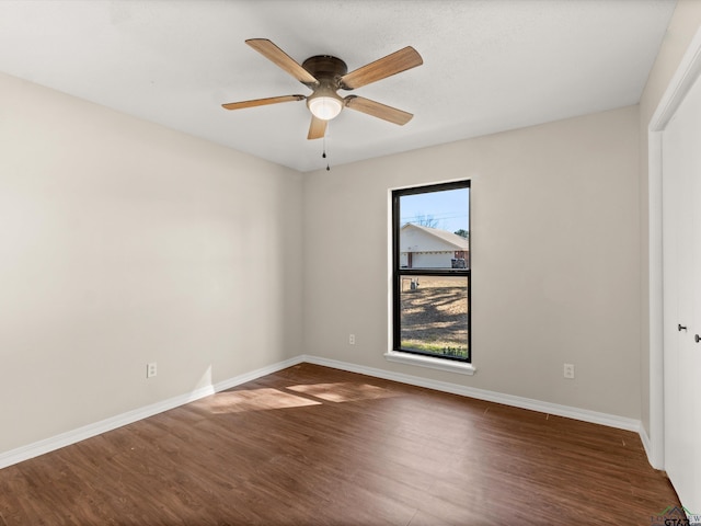 unfurnished room with a ceiling fan, baseboards, and dark wood-style flooring