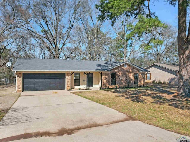 single story home featuring brick siding, a front lawn, an attached garage, and driveway