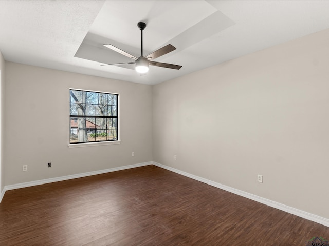 spare room with dark wood finished floors, ceiling fan, and baseboards