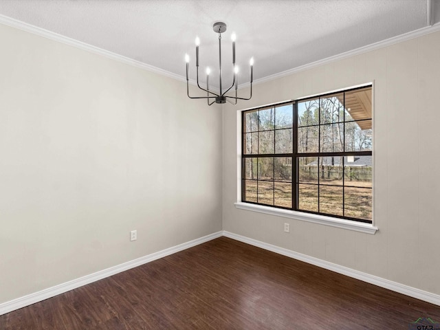 spare room featuring baseboards, dark wood-type flooring, a chandelier, and ornamental molding