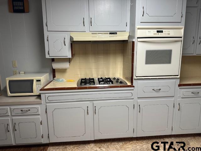 504 Mt Sylvan, Lindale, TX 75771 - kitchen featuring white appliances, under cabinet range hood, and tasteful backsplash