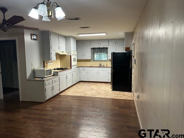 504 Mt Sylvan, Lindale, TX 75771 - kitchen with white appliances, wood finished floors, a chandelier, decorative backsplash, and wooden walls