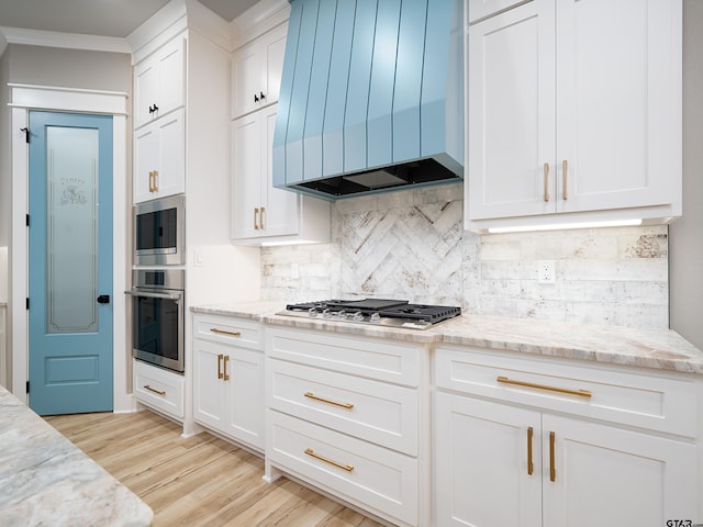 328 Heritage Way, Bullard, TX 75757 - kitchen with appliances with stainless steel finishes, wall chimney exhaust hood, white cabinets, tasteful backsplash, and light wood-type flooring