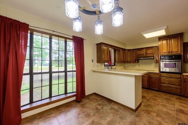 16850 Rainbow Ridge Cir, Tyler, TX 75707 - kitchen featuring oven, under cabinet range hood, light countertops, cooktop, and a peninsula