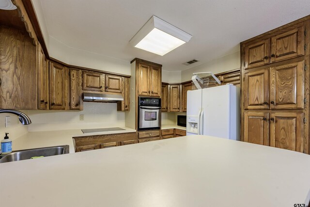 16850 Rainbow Ridge Cir, Tyler, TX 75707 - kitchen featuring oven, white fridge with ice dispenser, a sink, under cabinet range hood, and stovetop