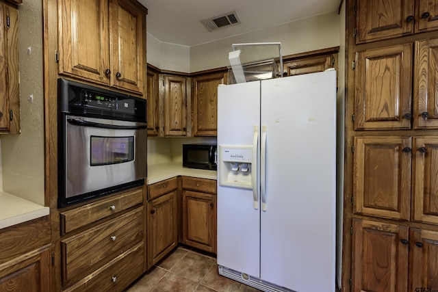 16850 Rainbow Ridge Cir, Tyler, TX 75707 - kitchen featuring white fridge with ice dispenser, stainless steel oven, black microwave, and brown cabinets